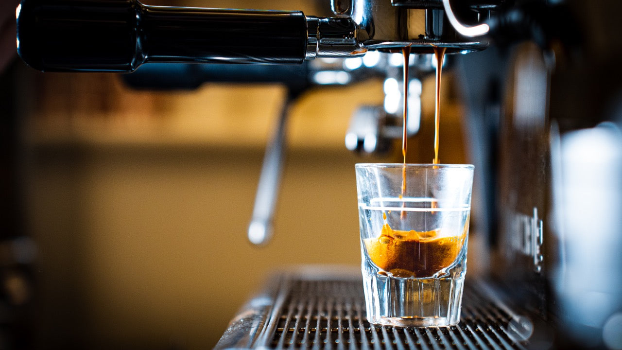 Bottomless portafilter pouring a coffee shot into a small shot glass